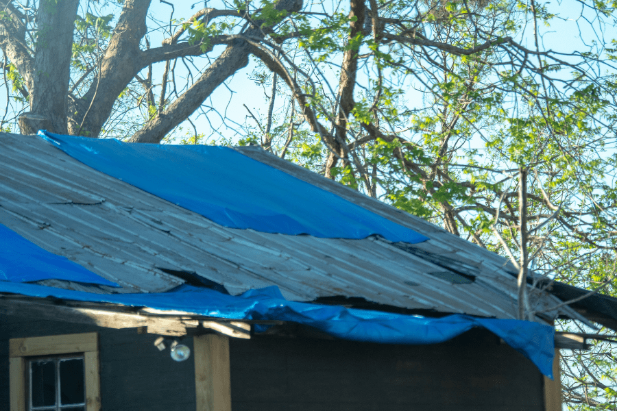 Roof leak showing a metal roof covered with tarps in a number of places.